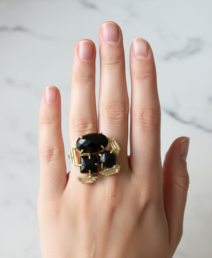 Black Onyx Triple Stone Statement Ring – Handcrafted Gold Cocktail Ring 1 Top-down view of a gold ring with three black onyx stones of different shapes and textures
