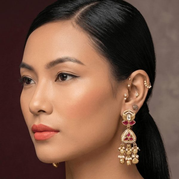 "Woman wearing traditional kundan emerald drop earrings with gold detailing and ethnic design"