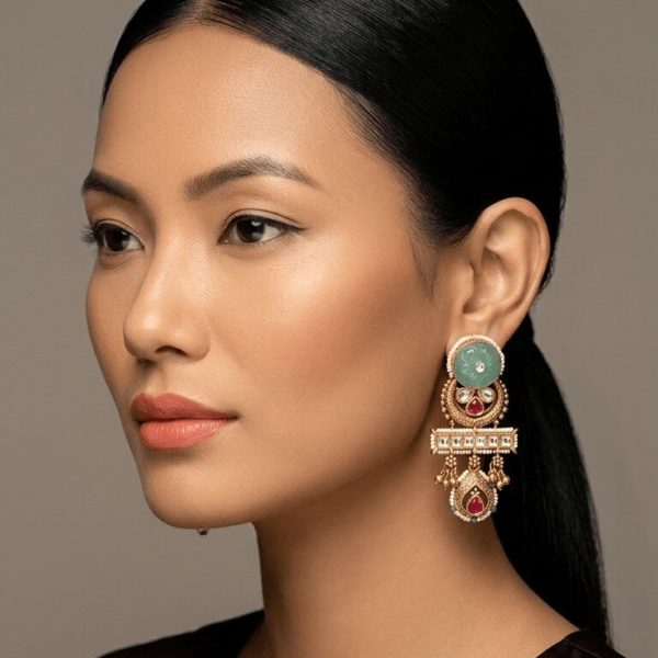 "Woman wearing traditional kundan emerald drop earrings with gold detailing and ethnic design"
