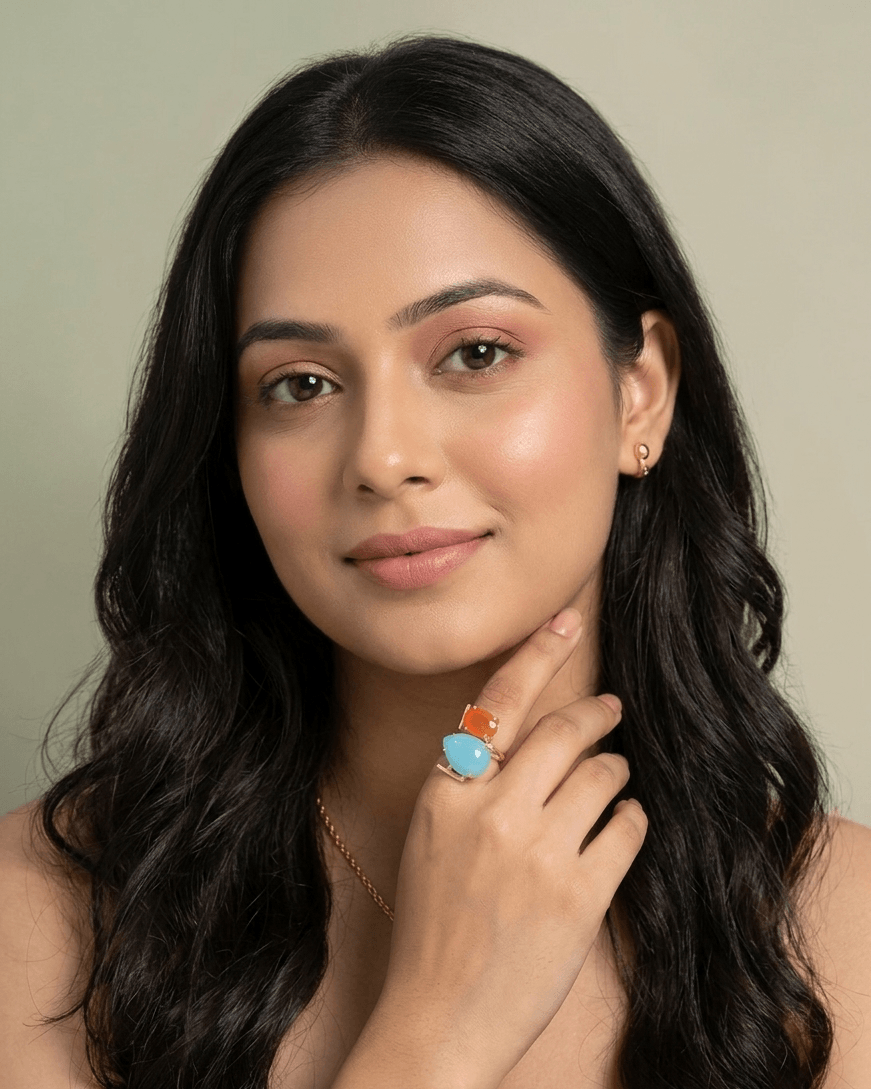 Aqua Chalcedony and Orange Carnelian Architectural Statement Ring – Handcrafted Gold Geometric Dual-Stone Ring 1 A lifestyle close-up of a woman wearing an intricate gold geometric ring featuring a large light blue teardrop stone and a rectangular orange stone.