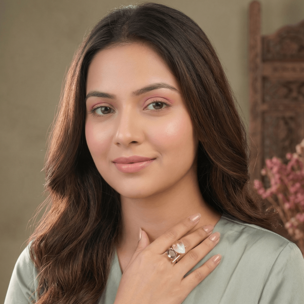 A lifestyle close-up of a woman wearing a large gold geometric ring by Belsi's Jewelry featuring a white moonstone and a faceted Rose Quartz gemstone.