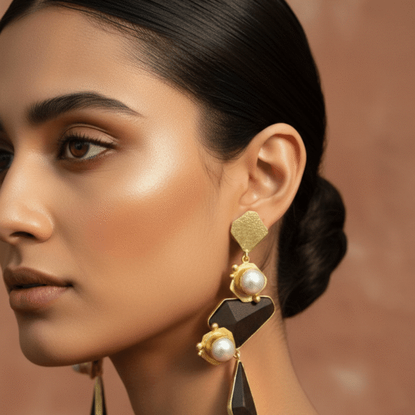 A close-up profile of a woman wearing tiered geometric earrings featuring dark wood accents and lustrous pearls