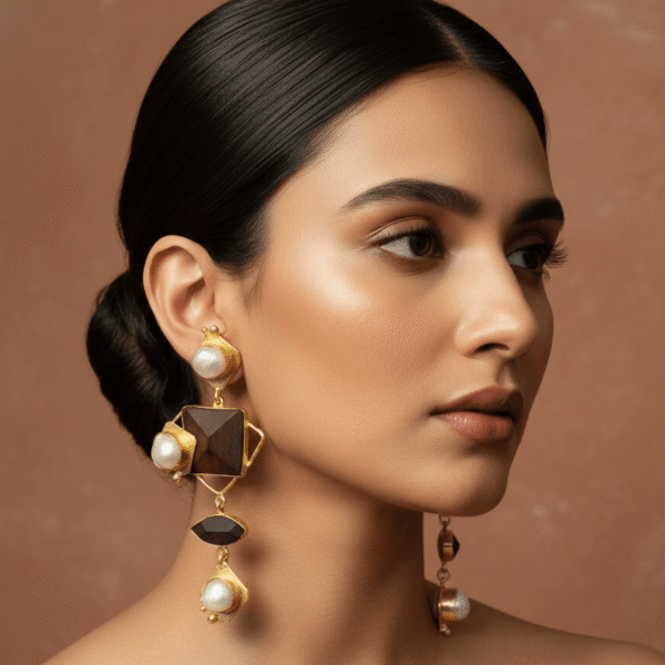 Close-up of a model wearing tiered geometric earrings featuring dark rosewood accents, gold-toned settings, and lustrous white baroque pearls.
