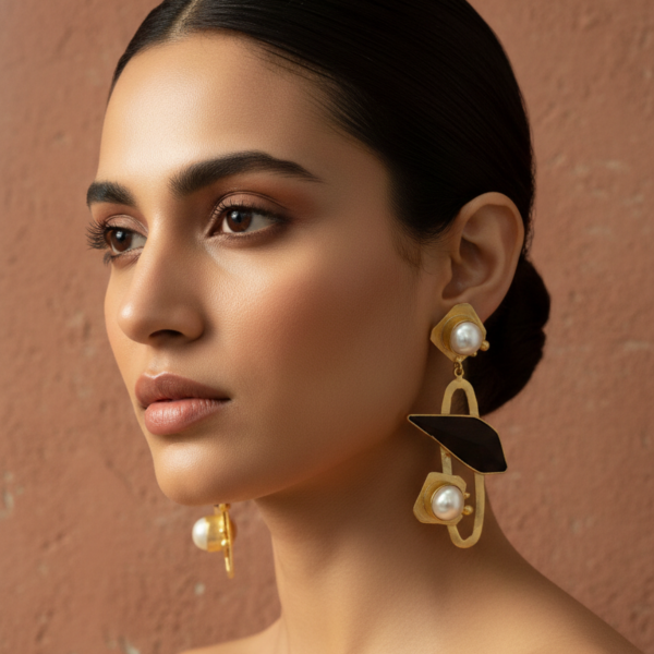 Model wearing sophisticated gold-tone geometric drop earrings with white baroque pearl on rosewood