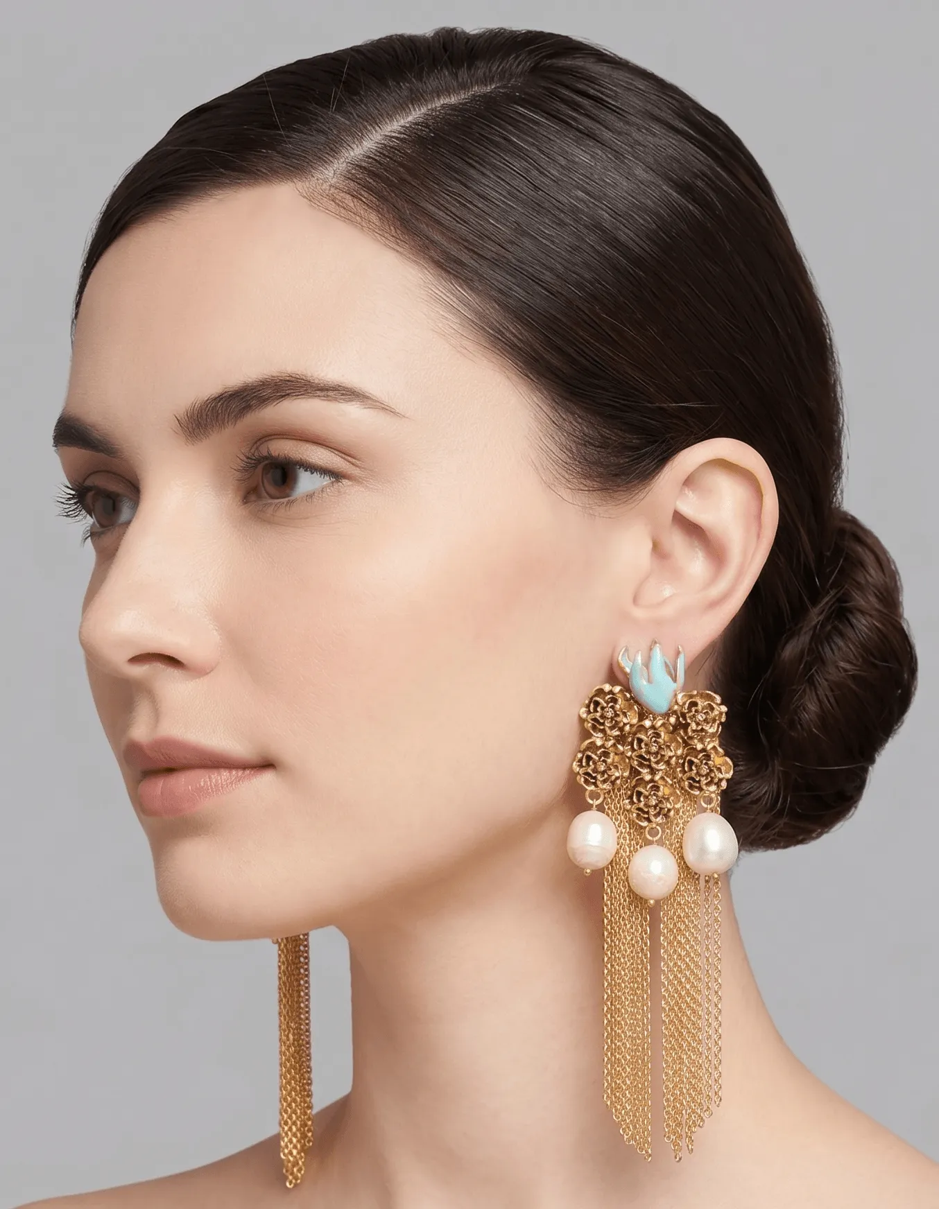 Flower Power Gold Filigree Tassel Earrings with Turquoise Enamel & Pearls 1 Studio profile portrait of a model showcasing Belsi's Jewelry Flower Power collection long gold tassel earrings featuring intricate textured floral filigree studs, light turquoise blue enamel accents, and three hanging freshwater pearls with fluid chain fringes.