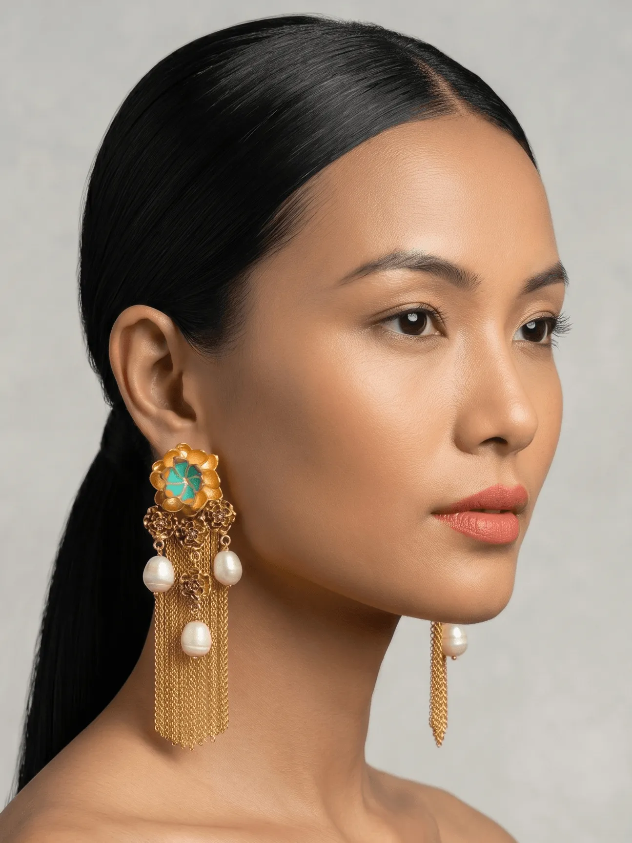 Flower Power Tiered Floral Filigree Tassel Earrings with Turquoise Enamel 1 Close-up profile portrait of a model showcasing Belsi's Jewelry Flower Power collection long statement earrings, featuring a large tiered gold flower stud with turquoise blue enamel petals, a cluster drop of smaller filigree roses, multiple hanging round freshwater pearls, and long fluid gold chain fringe tassels.