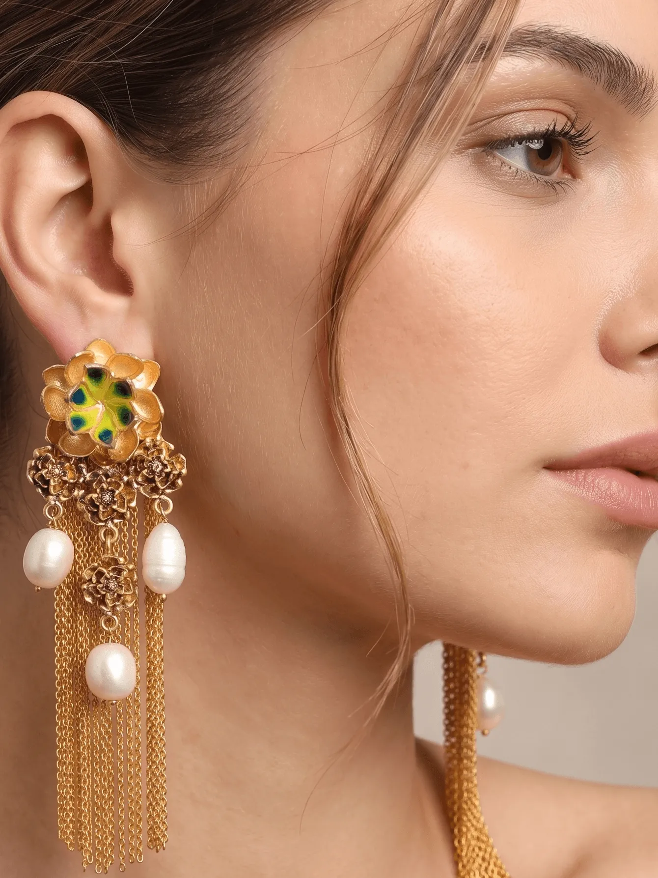 Flower Power Tiered Floral Filigree Tassel Earrings with Lime & Peacock Green Enamel 1 Extreme close-up portrait of a model showcasing Belsi's Jewelry Flower Power collection long statement earrings, featuring a large tiered gold flower stud with hand-painted lime yellow-green and deep peacock green enamel petals, a cluster drop of smaller filigree roses, hanging baroque freshwater pearls, and long fluid gold chain fringe tassels.