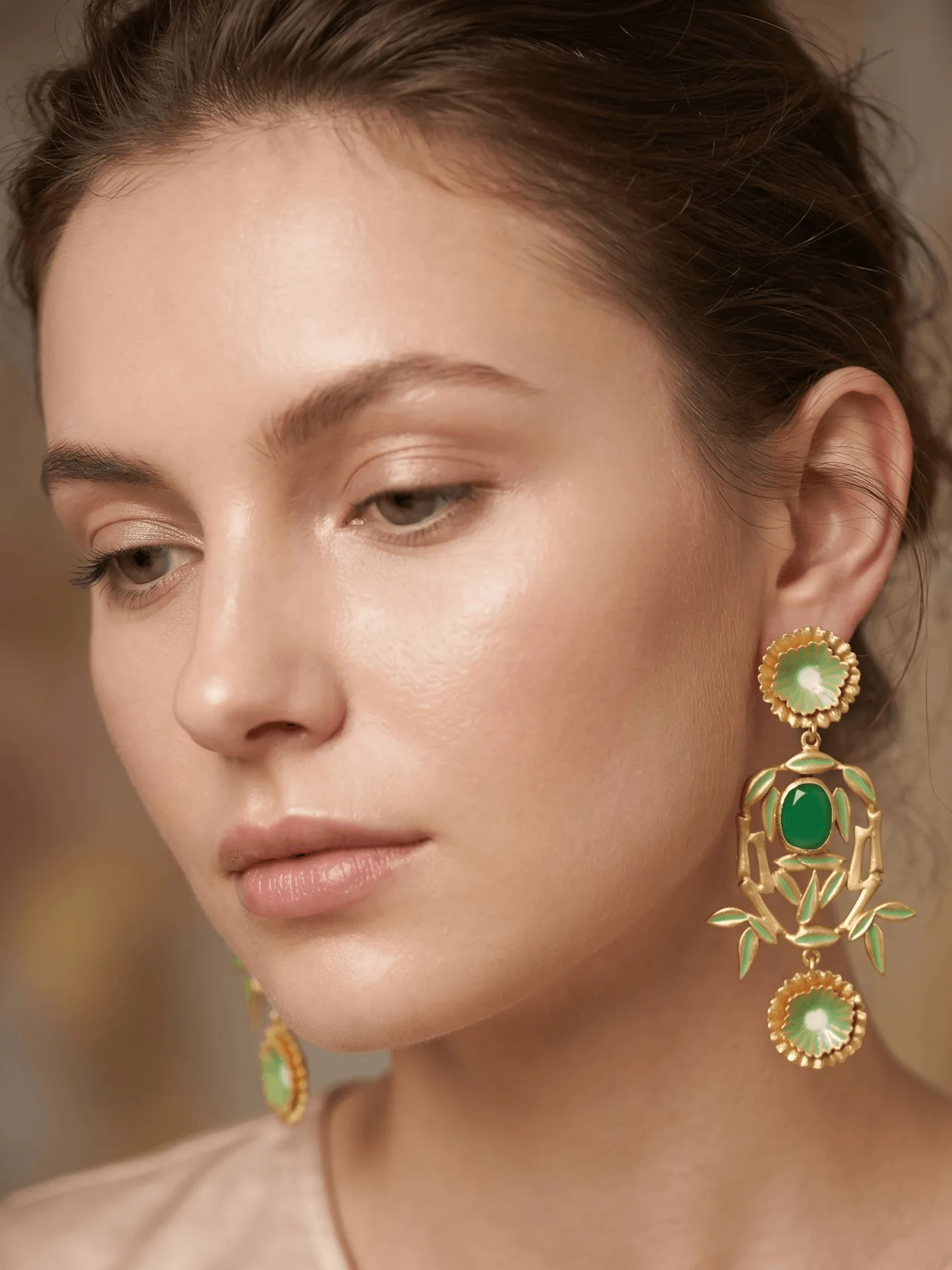Imperial Enamelled Bamboo Chandelier Earrings in Gold-Tone with Jade Green Gemstones 1 Close-up of a model wearing large, ornate gold-tone chandelier statement earrings featuring dual pastel green enamel floral disks, a central framing bamboo arch, and a vibrant jade green oval cabochon stone.