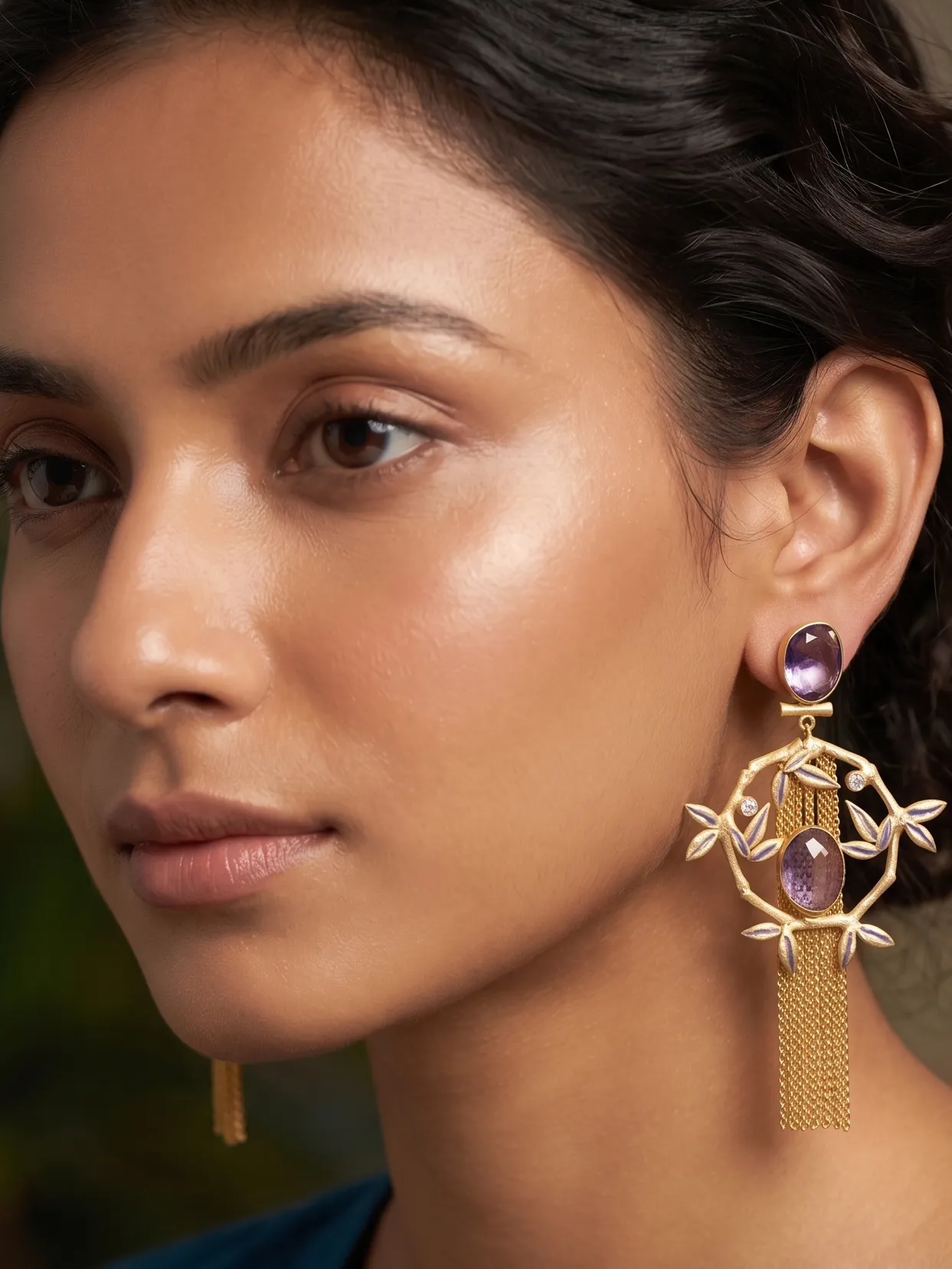 Luminary Enamelled Bamboo Diamond Fringe Earrings with Purple Amethyst Gemstones 1 Close-up of a model wearing long gold-tone statement fringe earrings featuring an oval faceted purple amethyst stud, a dangling diamond-shaped bamboo frame accented with soft lavender enamel leaves, a central matching oval purple gemstone, and a long cascading waterfall of fine gold chain tassels.