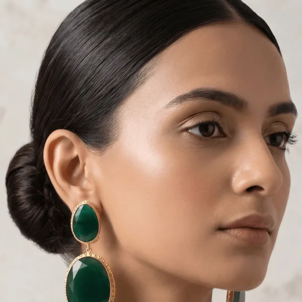 Editorial portrait model wearing handcrafted emerald green double drop statement earrings with faceted oval stones and textured gold frames from the Belsi Spectrum Luxe Collection.