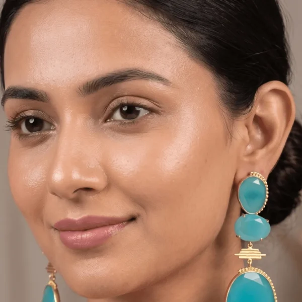 Belsi's Jewelry three-tier statement drop earrings featuring vibrant aqua blue quartz stones encased in handcrafted gold-plated borders.
