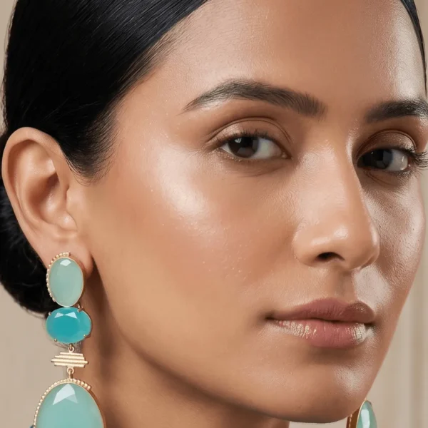 Model styling Belsi's Jewelry seafoam green and turquoise blue quartz three-tier drop earrings featuring handcrafted gold-plated borders.