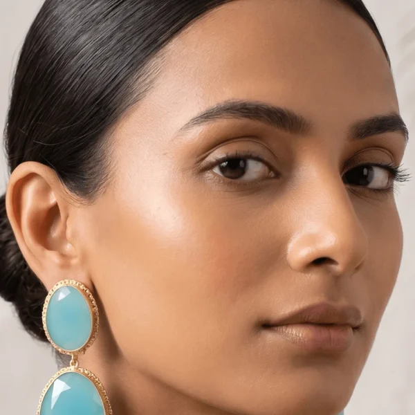 Belsi's Jewelry two-tier statement drop earrings featuring an oval sky blue quartz top stone and a large, faceted aqua blue teardrop crystal encased in handcrafted gold-plated borders.