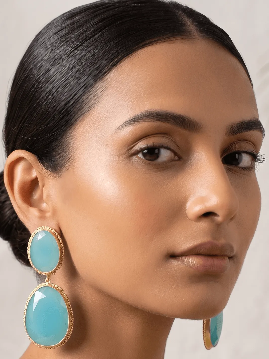 Aqua Blue Quartz Two-Tier Drop Earrings 1 Belsi's Jewelry two-tier statement drop earrings featuring an oval sky blue quartz top stone and a large, faceted aqua blue teardrop crystal encased in handcrafted gold-plated borders.